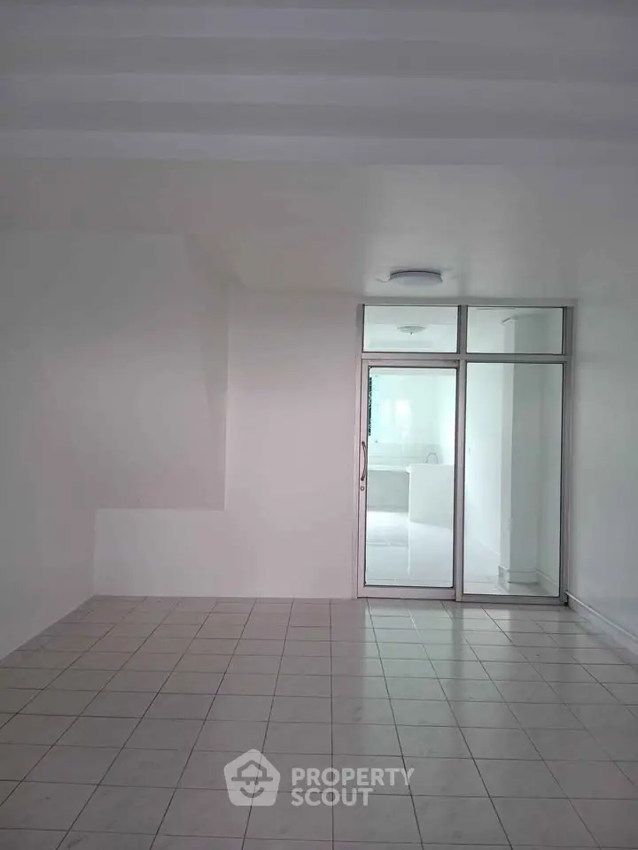 Spacious tiled room with sliding glass doors leading to a bright area, ideal for modern living.