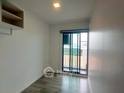 Spacious bedroom with large window and balcony access in modern apartment.