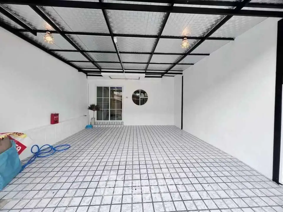 Spacious covered parking area with modern tiled flooring and ceiling lights.