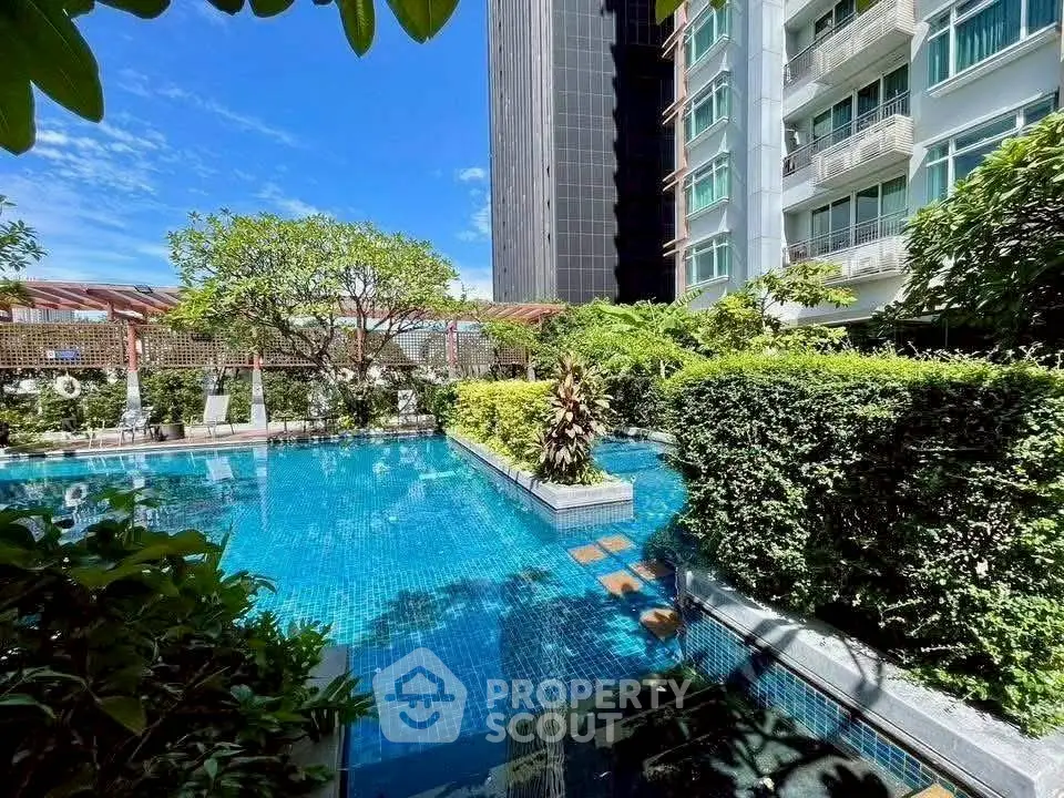 Luxurious residential pool area with lush greenery and modern architecture.