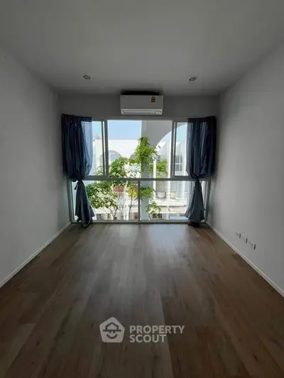 Spacious empty room with large windows and wooden flooring, perfect for customization.
