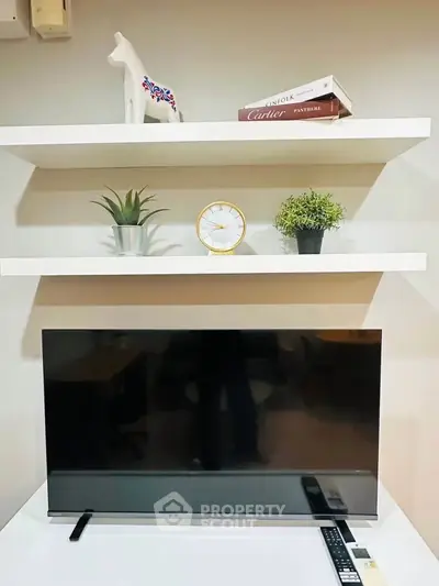 Modern living room with sleek TV setup and stylish decor on floating shelves.