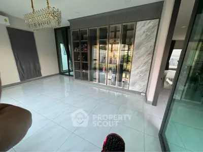 Spacious modern living room with elegant chandelier and large glass cabinet
