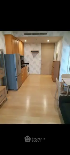 Modern kitchen with wooden cabinets and dining area in a cozy apartment.