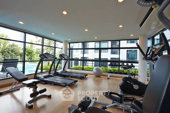 Modern gym with large windows and fitness equipment in a residential building.