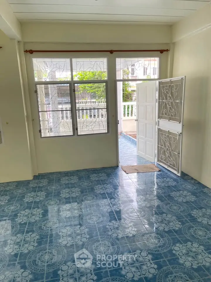 Bright living room with blue patterned tile floor and open door to balcony.