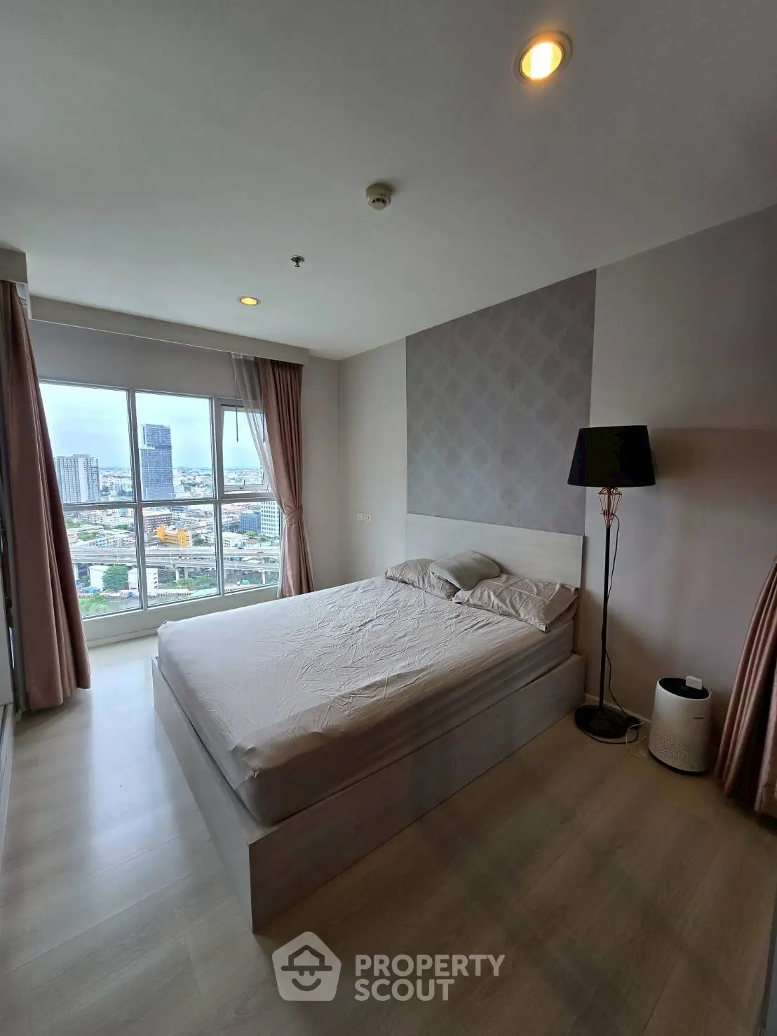 Spacious bedroom with city view and modern decor in high-rise apartment