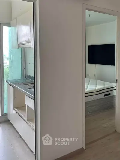 Compact apartment interior with kitchenette and bedroom featuring modern design and natural light.
