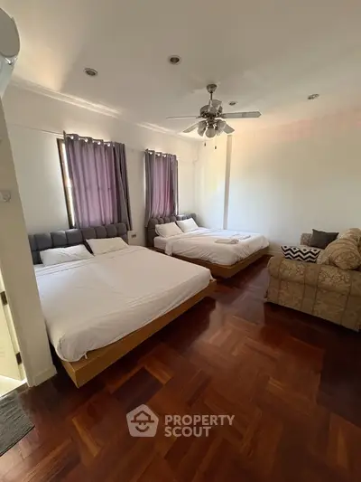 Spacious bedroom with two beds and cozy seating area, perfect for relaxation.