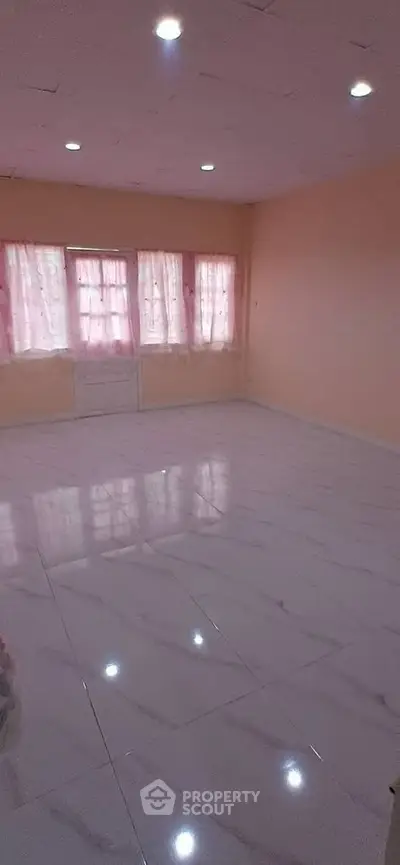 Spacious empty room with tiled flooring and large windows, ideal for customization.