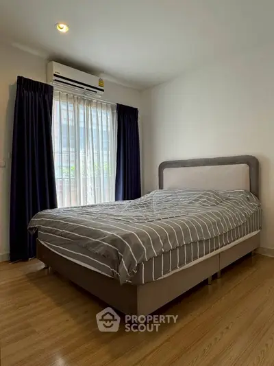 Cozy bedroom with modern decor and natural light, featuring a comfortable bed and elegant curtains.