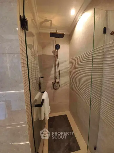 Luxurious modern bathroom with glass shower enclosure and elegant fixtures.