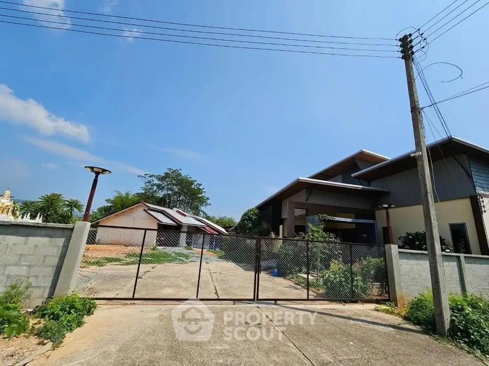 Modern residential property with gated entrance and spacious driveway under clear blue sky.