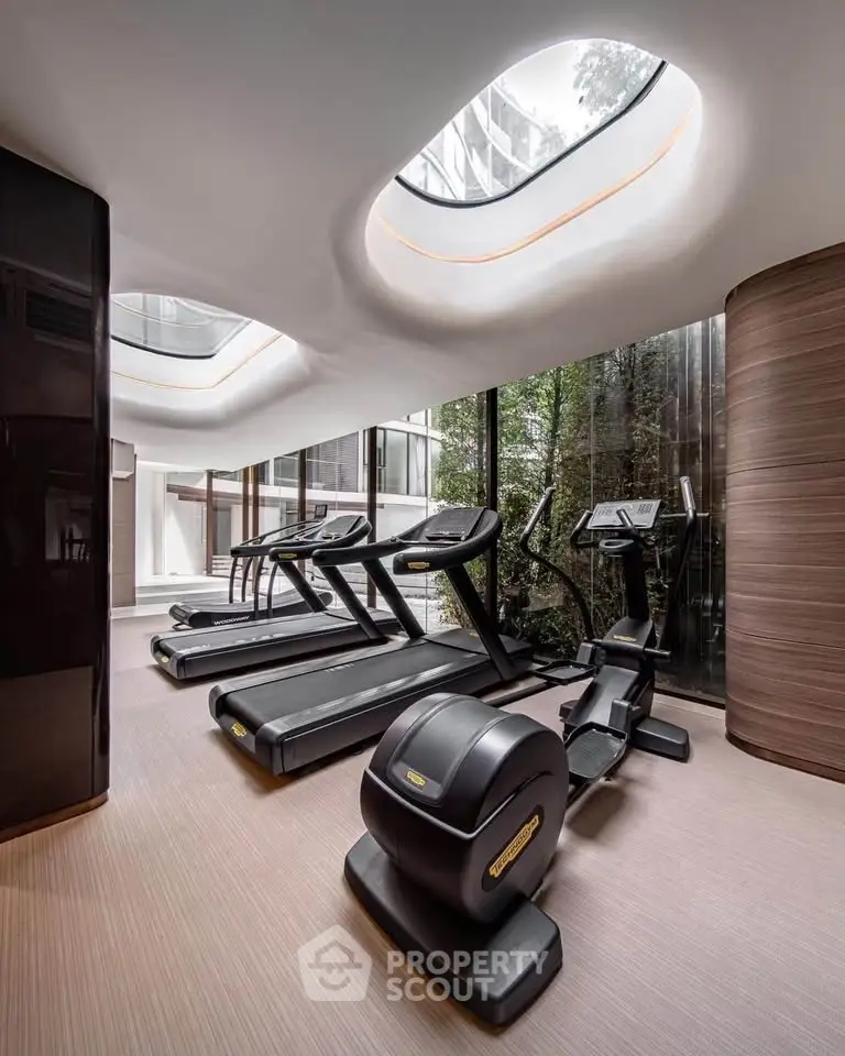 Luxurious gym with modern equipment and skylight in upscale residential building.