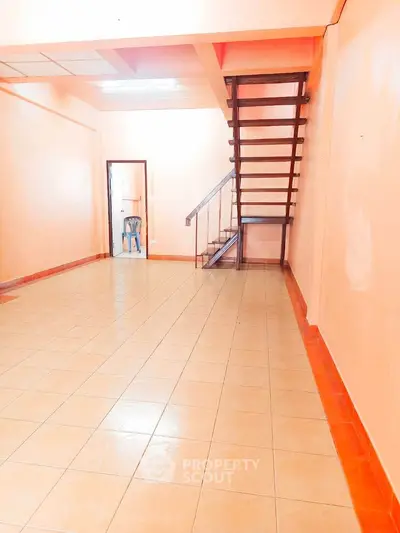 Spacious interior with tiled flooring and staircase, ideal for versatile living arrangements.