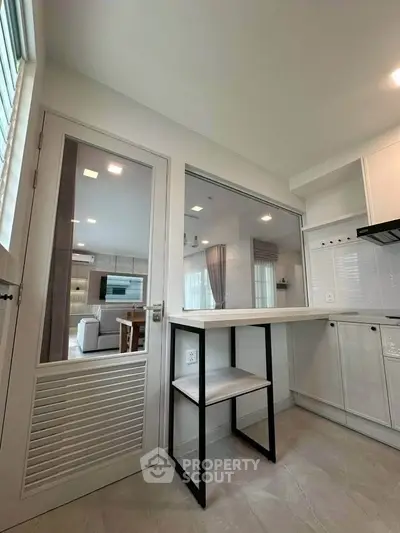 Modern kitchen with open layout and sleek design, featuring a breakfast bar and view into the living room.