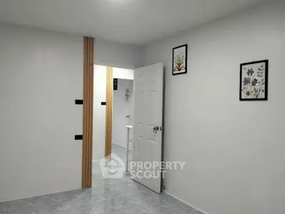 Minimalist interior with white walls and door, featuring floral wall art and tiled flooring.