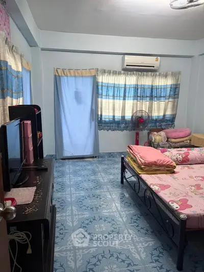 Cozy bedroom with air conditioning and colorful decor, featuring a comfortable bed and ample natural light.