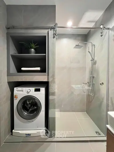 Modern bathroom with integrated washing machine and sleek shower design.