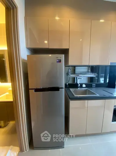Modern kitchen with sleek cabinetry and stainless steel fridge in a stylish apartment.