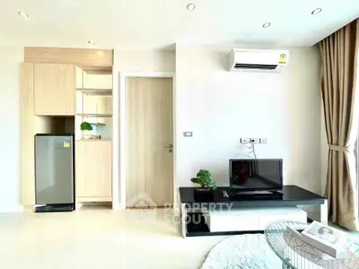 Modern living room with sleek design, featuring air conditioning and compact kitchen area.