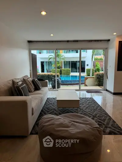 Spacious living room with pool view, modern sofa, and elegant decor in luxury apartment.