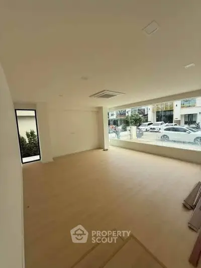 Spacious unfurnished room with large window and street view, ideal for customization.