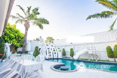 Luxurious outdoor pool area with slide and tropical landscaping