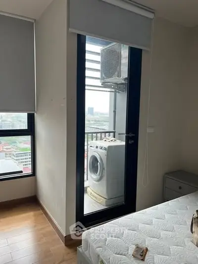 Modern bedroom with balcony view and washing machine, featuring sleek design and natural light.