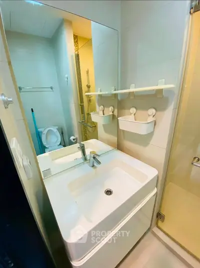 Compact modern bathroom with sleek fixtures and a large mirror, maximizing space efficiency.