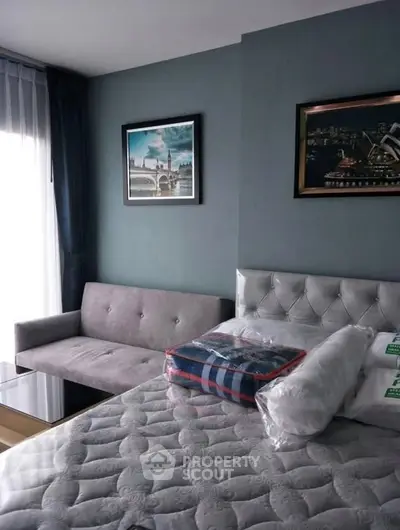 Modern bedroom with stylish decor and natural light, featuring a cozy sofa and elegant wall art.