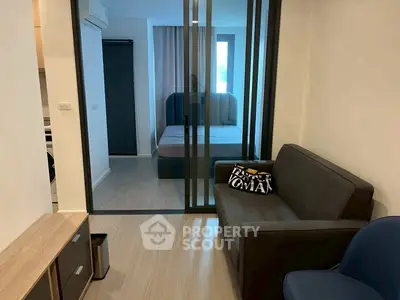 Modern studio apartment with glass partition, cozy sofa, and stylish decor.