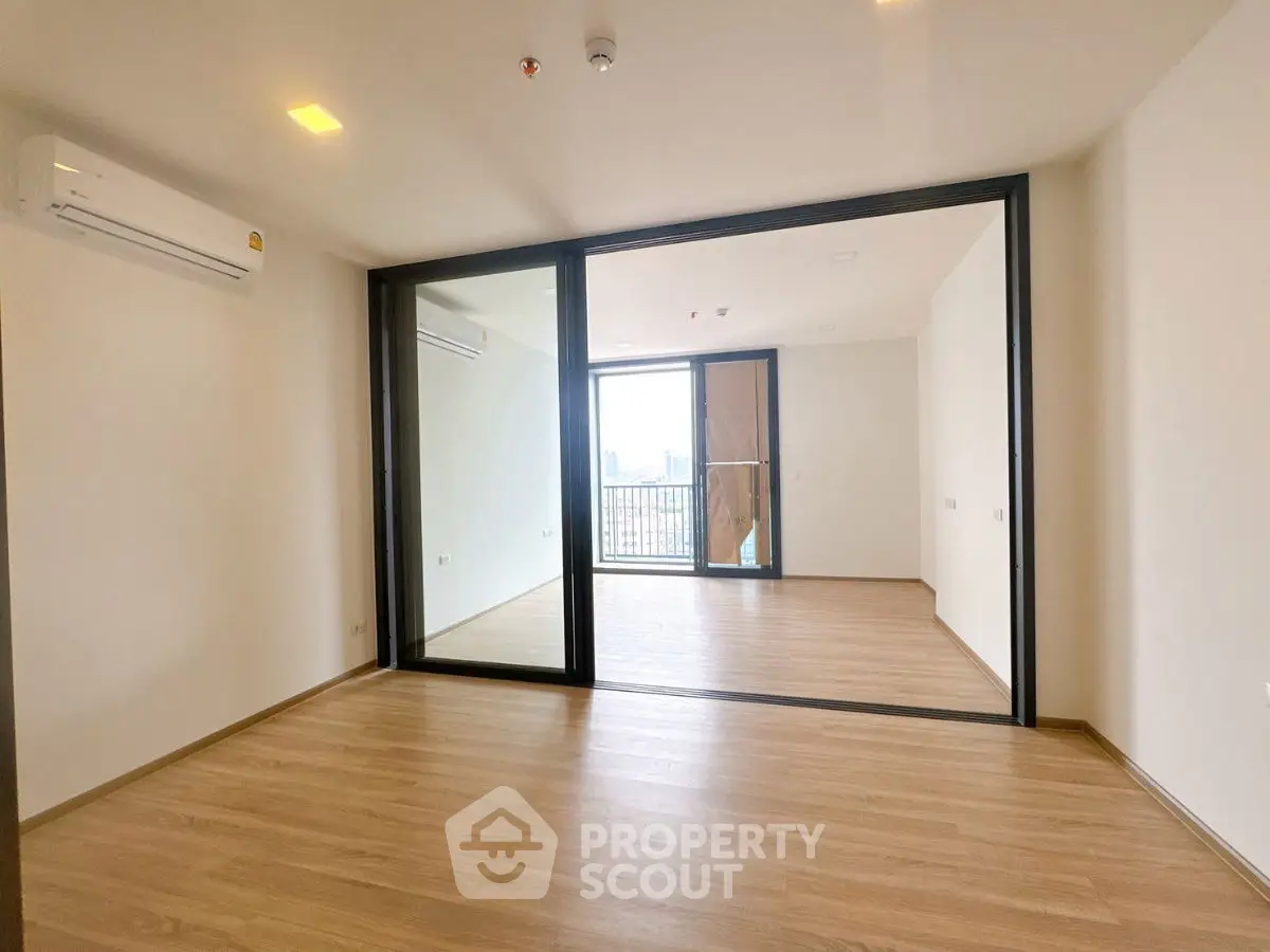 Spacious modern living room with wooden flooring and large glass doors to balcony.