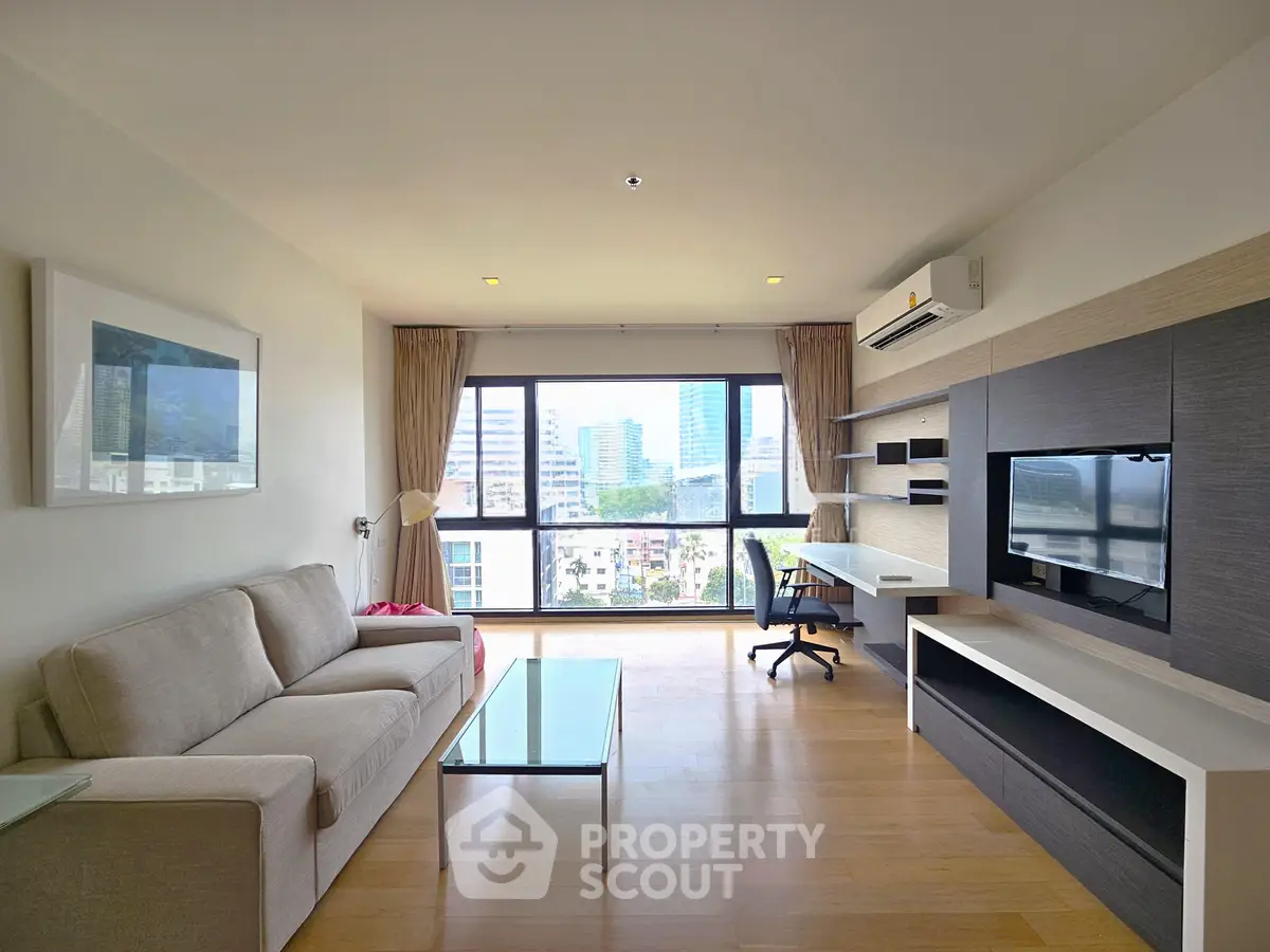 Spacious modern living room with city view, featuring sleek furniture and large windows.