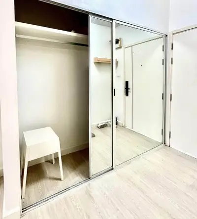Spacious mirrored closet in modern bedroom with light wood flooring.