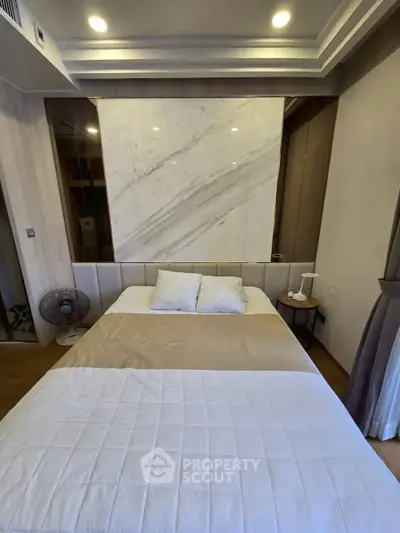 Modern bedroom with elegant marble accent wall and cozy bedding