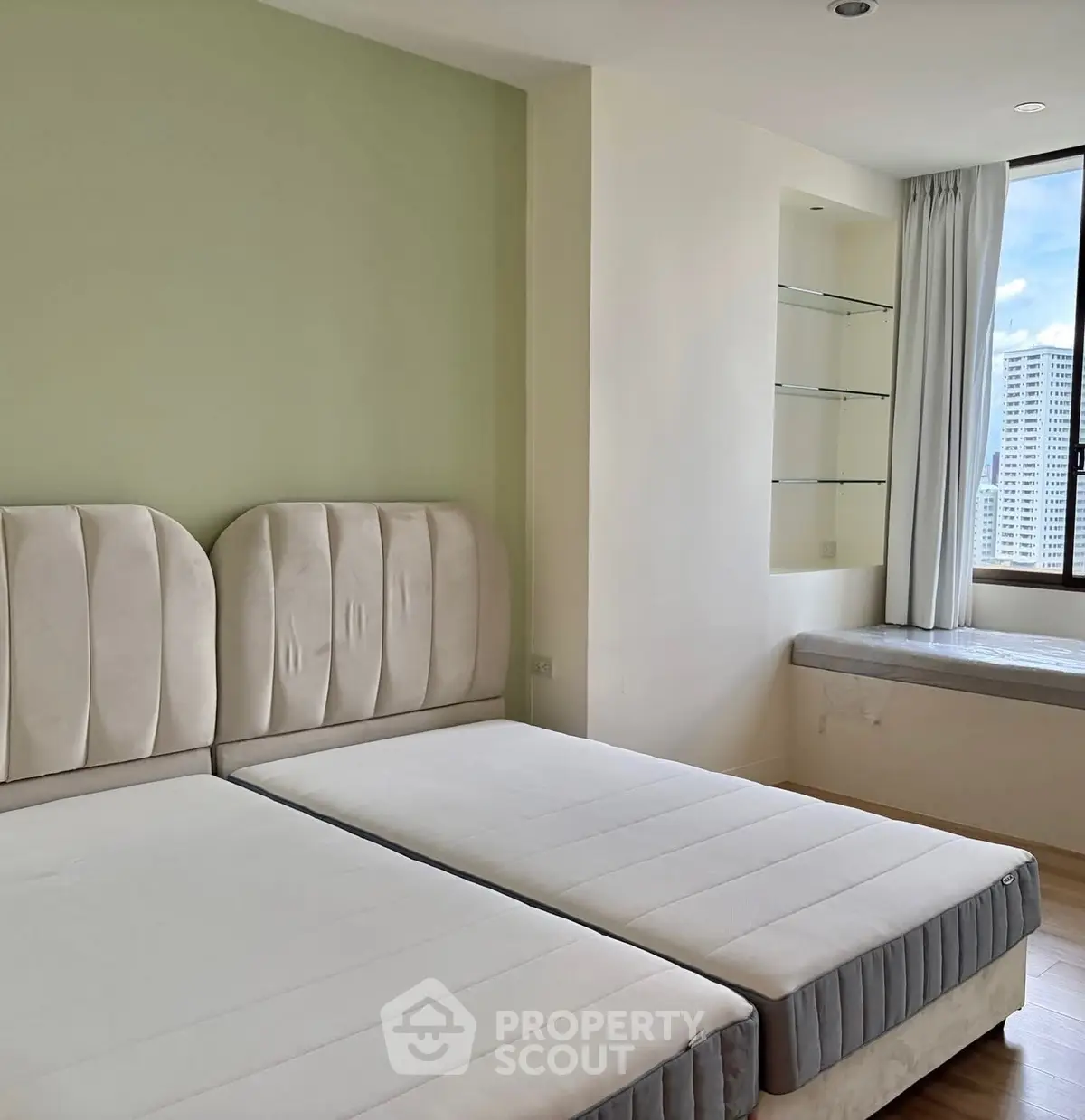 Spacious bedroom with twin beds and city view, perfect for urban living.