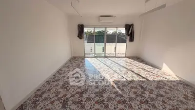 Spacious room with patterned tile flooring and large windows offering natural light.