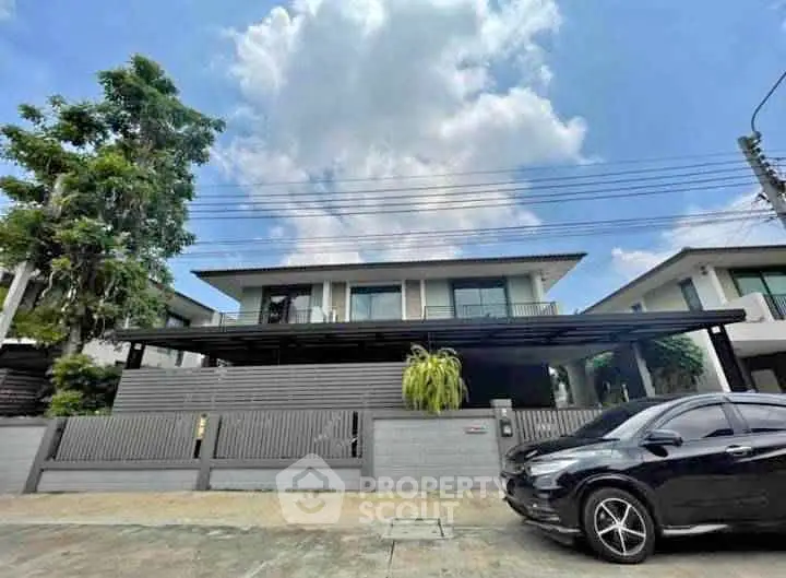 Modern two-story house with sleek design and spacious driveway in suburban neighborhood.
