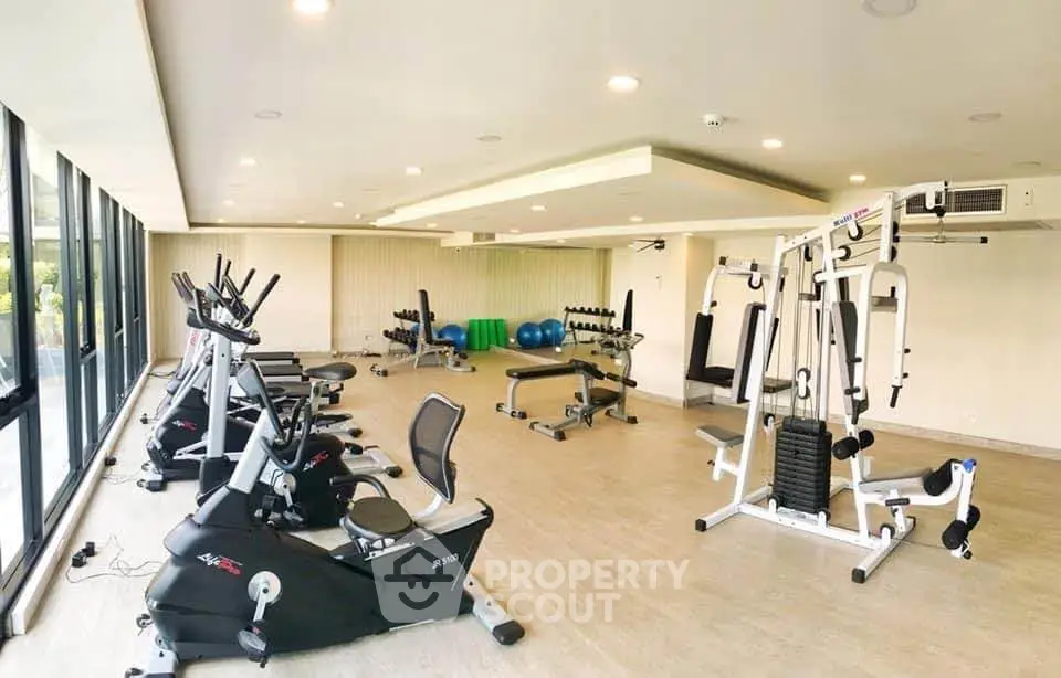 Spacious modern gym with state-of-the-art fitness equipment and large windows for natural light.