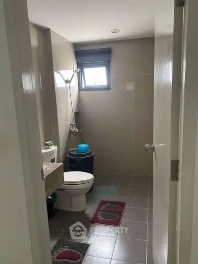Modern bathroom with sleek tiles and natural light from window.