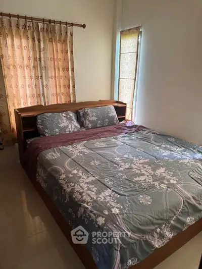 Cozy bedroom with floral curtains and comfortable bedding, perfect for relaxation.