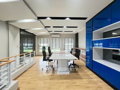 Modern office space with sleek design and ample natural light, featuring stylish furniture and blue cabinetry.