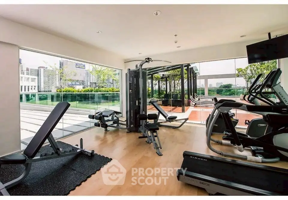 Modern gym with city view and state-of-the-art equipment in luxury apartment complex.