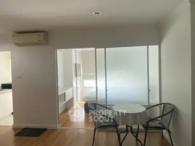 Cozy apartment interior with dining area and frosted glass sliding doors leading to bedroom.