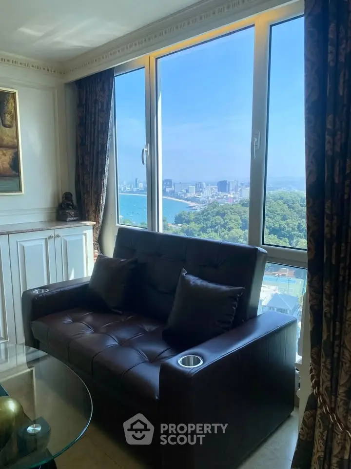 Luxurious living room with stunning city view through large windows, featuring elegant leather sofa and chic decor.