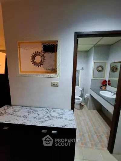 Modern bathroom with stylish mirror and marble countertop, featuring elegant tile flooring and contemporary fixtures.