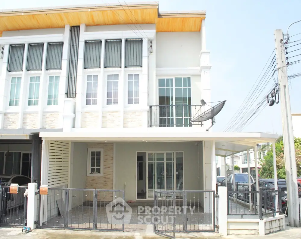 Modern townhouse exterior with gated parking and balcony in a suburban neighborhood.