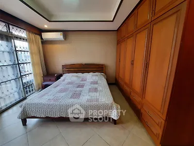 Spacious bedroom with large wooden wardrobe and cozy bed in a well-lit room.