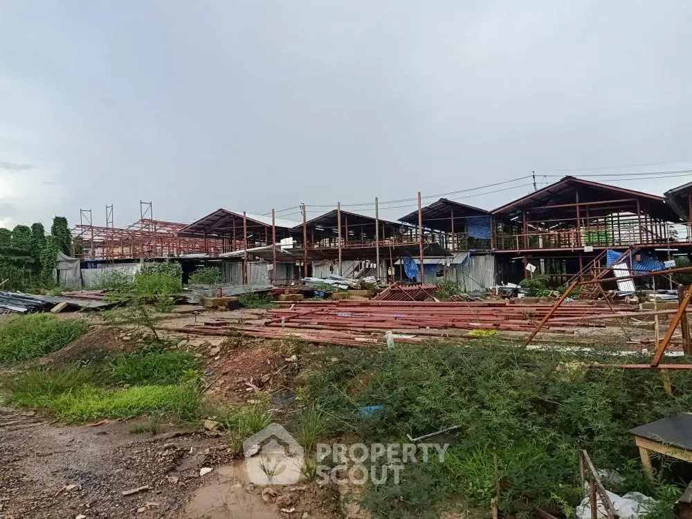 Construction site with steel framework and unfinished buildings under cloudy sky.